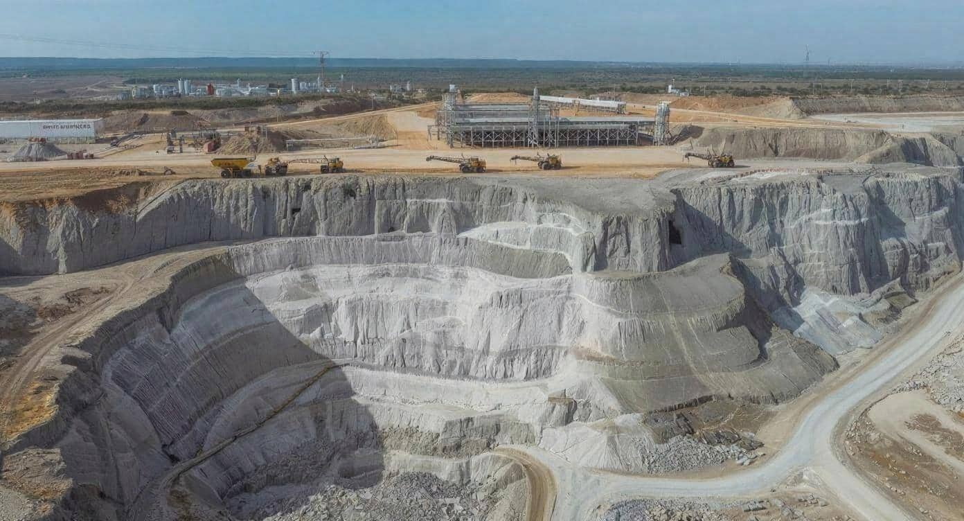 Aerial view of an African open-pit lithium mine showing terraced extraction levels, haul trucks, and mineral processing infrastructure supporting critical minerals production for the global battery supply chain.